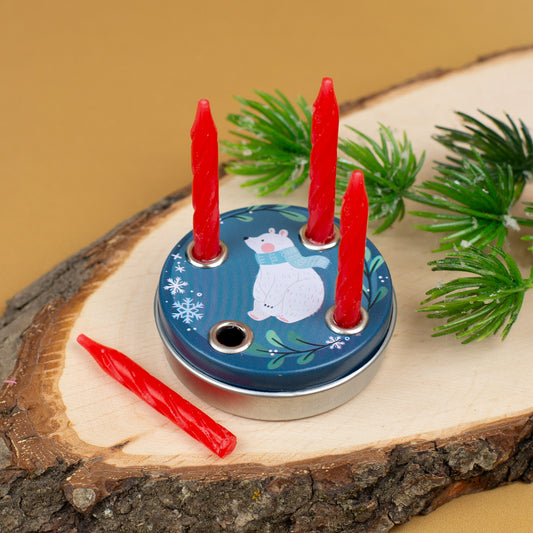 Adventskranz mit Eisbär-Motiv auf Holzscheibe, drei Kerzen stecken im Kranz, eine vierte liegt unbenutzt daneben, Tannenzweige als Dekoration.