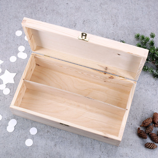 Geöffnete Holzbox mit Trennwand und Messingverschluss, dekoriert mit Tannenzweigen und Zapfen