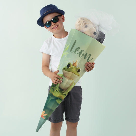 Junge mit Sonnenbrille hält eine personalisierte Froschkönig-Schultüte mit dem Namen "Leon"