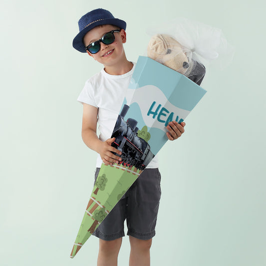 Junge mit Sonnenbrille und Dampflok-Zuckertüte in der Hand