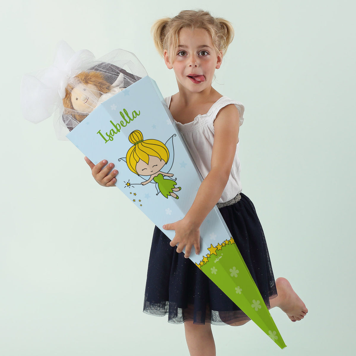 Mädchen hält große personalisierte Schultüte mit grün gekleideter Fee und dem Namen Isabella