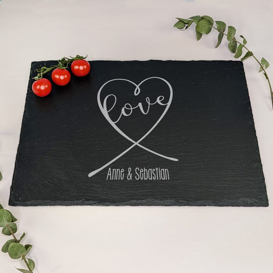 Schieferplatte mit Gravur „love“ in Herzform und „Anne & Sebastian“, dekoriert mit Tomaten und Eukalyptuszweig – auf hellem Untergrund
