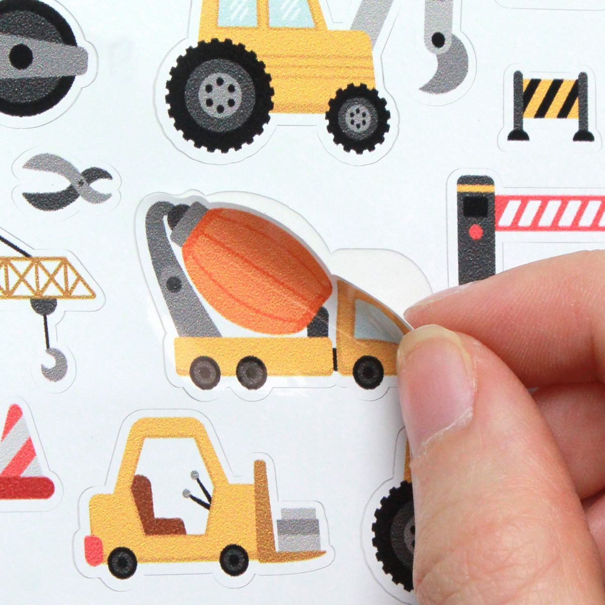 Detailaufnahme vom Abziehen eines Stickers des Stickerbogens der Baustellen-Motive