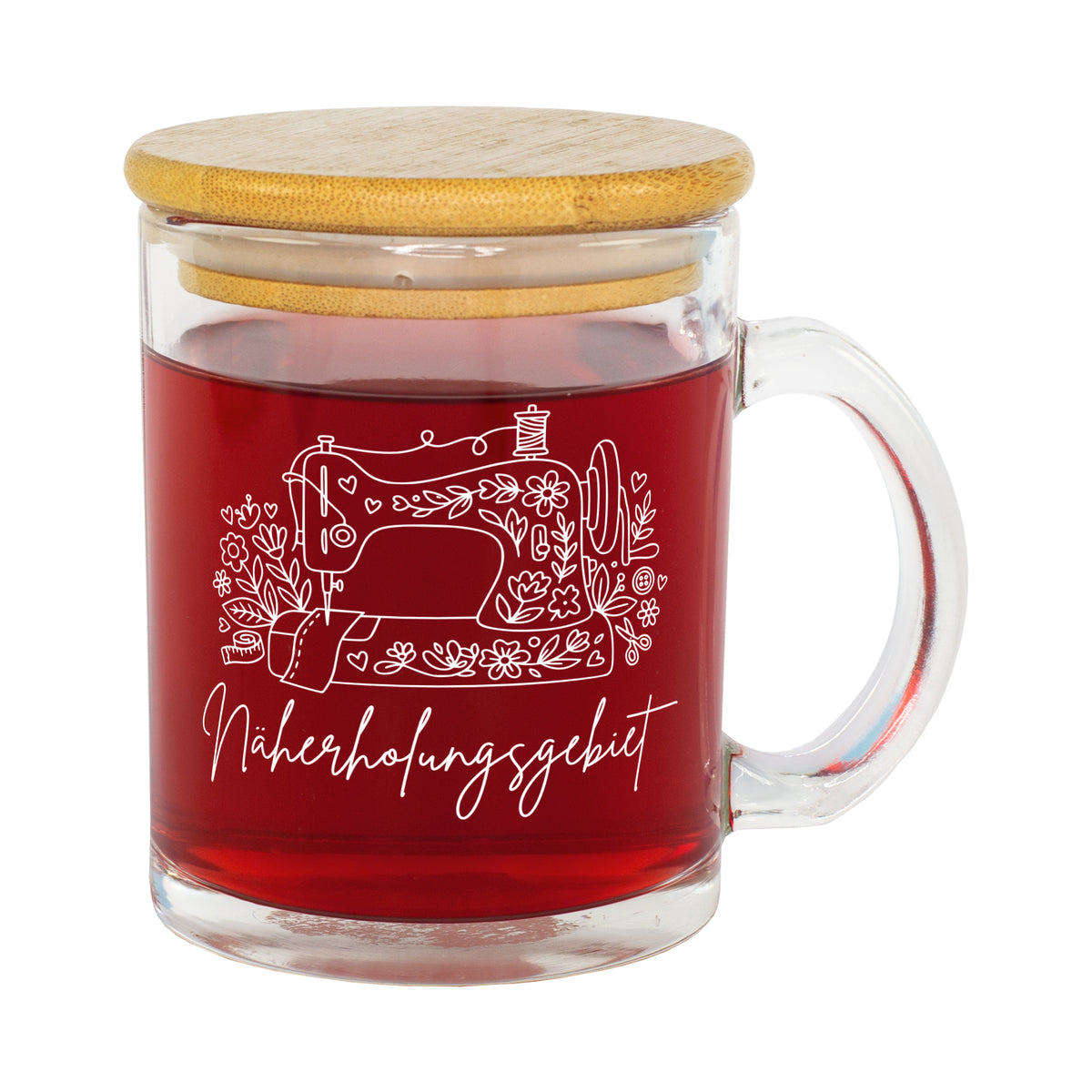 Freigestellte Glastasse mit rotem Tee, Bambusdeckel und weißem Nähmotiv „Näherholungsgebiet“
