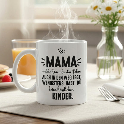 Weiße Kaffeetasse mit Mama-Spruch auf gedecktem Frühstückstisch mit Dampf und Tageslicht
