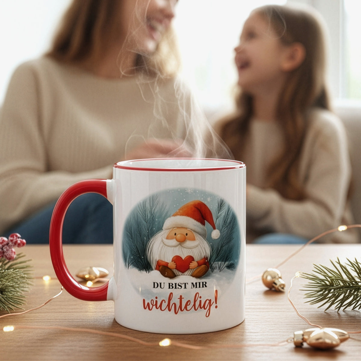 Weihnachtstasse mit Wichtelmotiv und Spruch „Du bist mir wichtelig!“ auf Holztisch, im Hintergrund Mutter und Tochter beim Lachen – stimmungsvolle Szene.