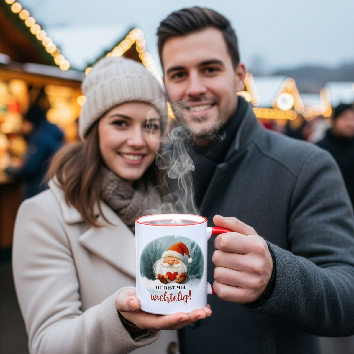 Paar auf Weihnachtsmarkt hält gemeinsam eine Tasse mit Wichtelmotiv und Spruch „Du bist mir wichtelig!“ – stimmungsvolles Geschenkfoto.