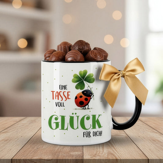 Tasse „Eine Tasse voll Glück für dich“ mit Pralinen dekoriert