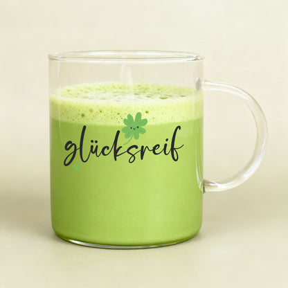 Großes Teeglas mit grünem Matcha-Getränk und „glücksreif“-Aufdruck
