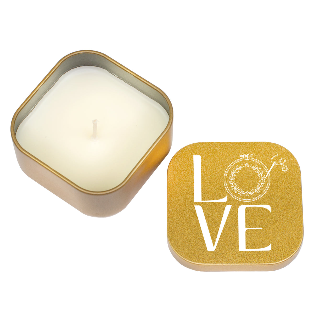 Freigestellte goldene Duftkerze mit weißem Wachs und LOVE Stickmotiv auf dem Deckel