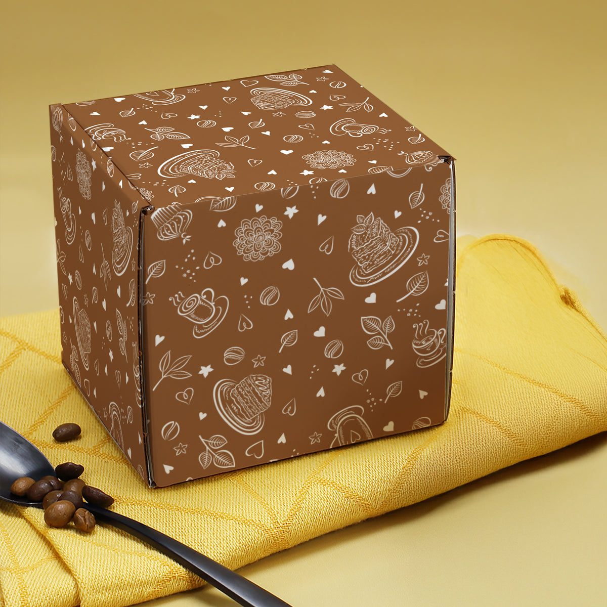 Braune Geschenkbox aus Pappe mit umlaufendem Kaffee-Motiv, frontal geschlossen dargestellt.