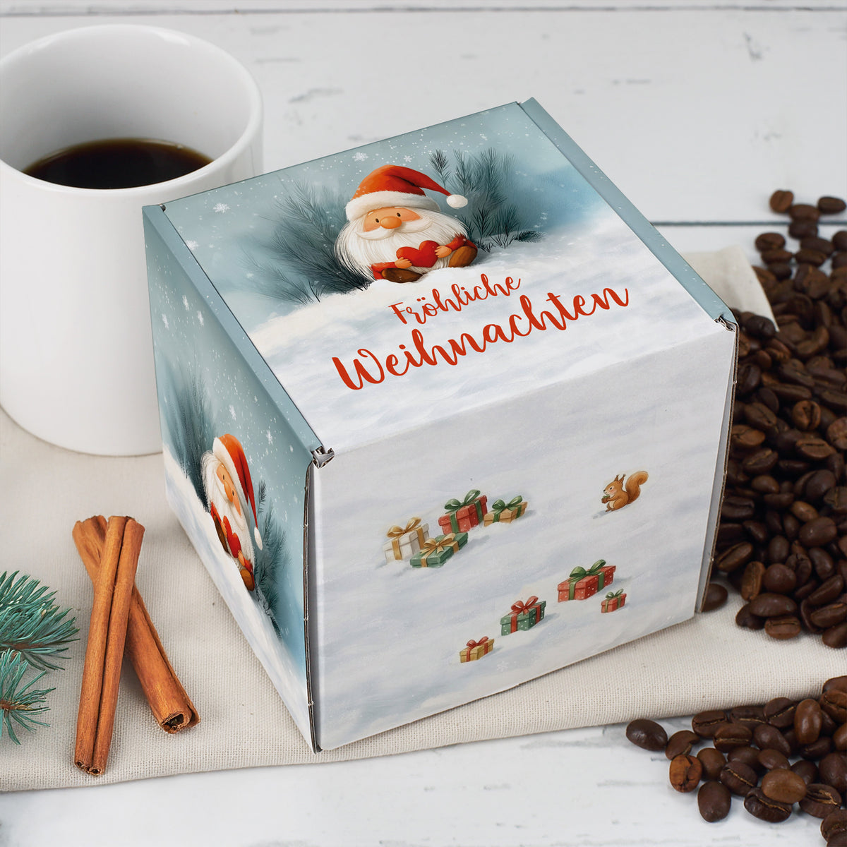 Quadratische Weihnachts-Geschenkbox mit Wichtelmotiv – Box neben Kaffeetasse und Zimtstangen