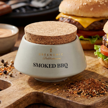 Greenomic Smoked BBQ Gewürzmischung im Keramiktopf mit Korkdeckel auf Holzbrett neben Burger