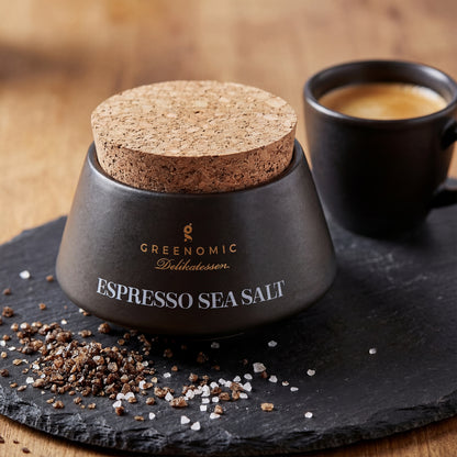 Premium Meersalz mit gemahlenem Kaffee im Keramikbehälter neben Espressotasse
