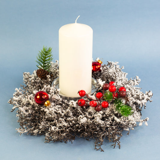 Adventskranz aus verschneiten Kunstzweigen mit Kerze und Weihnachtsdeko auf blauem Hintergrund