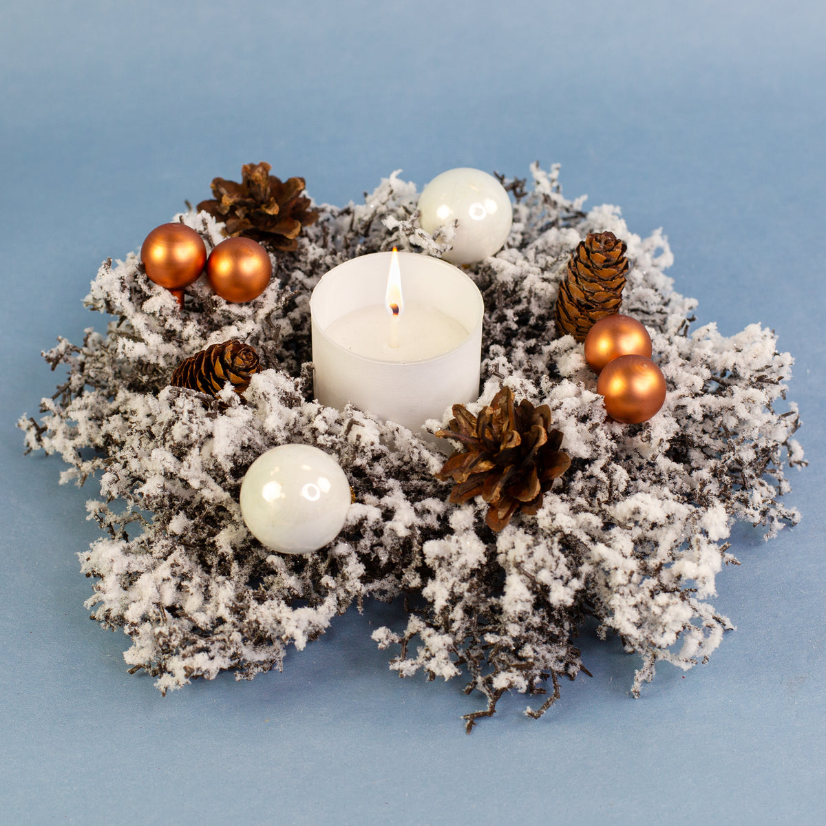 Adventskranz mit brennender Kerze, Tannenzapfen und Kugeln festlich dekoriert