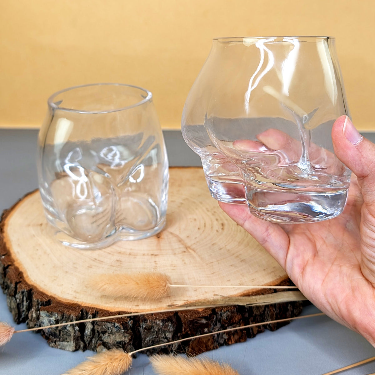 Hand hält eines der Gläser mit sichtbarem Gesäß-Motiv