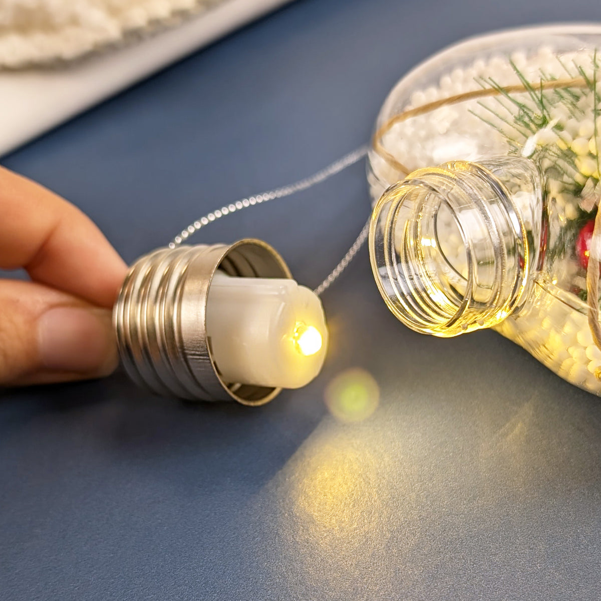 Nahaufnahme der glänzenden Metallaufhängung einer LED-Weihnachtskugel mit Deko-Füllung.