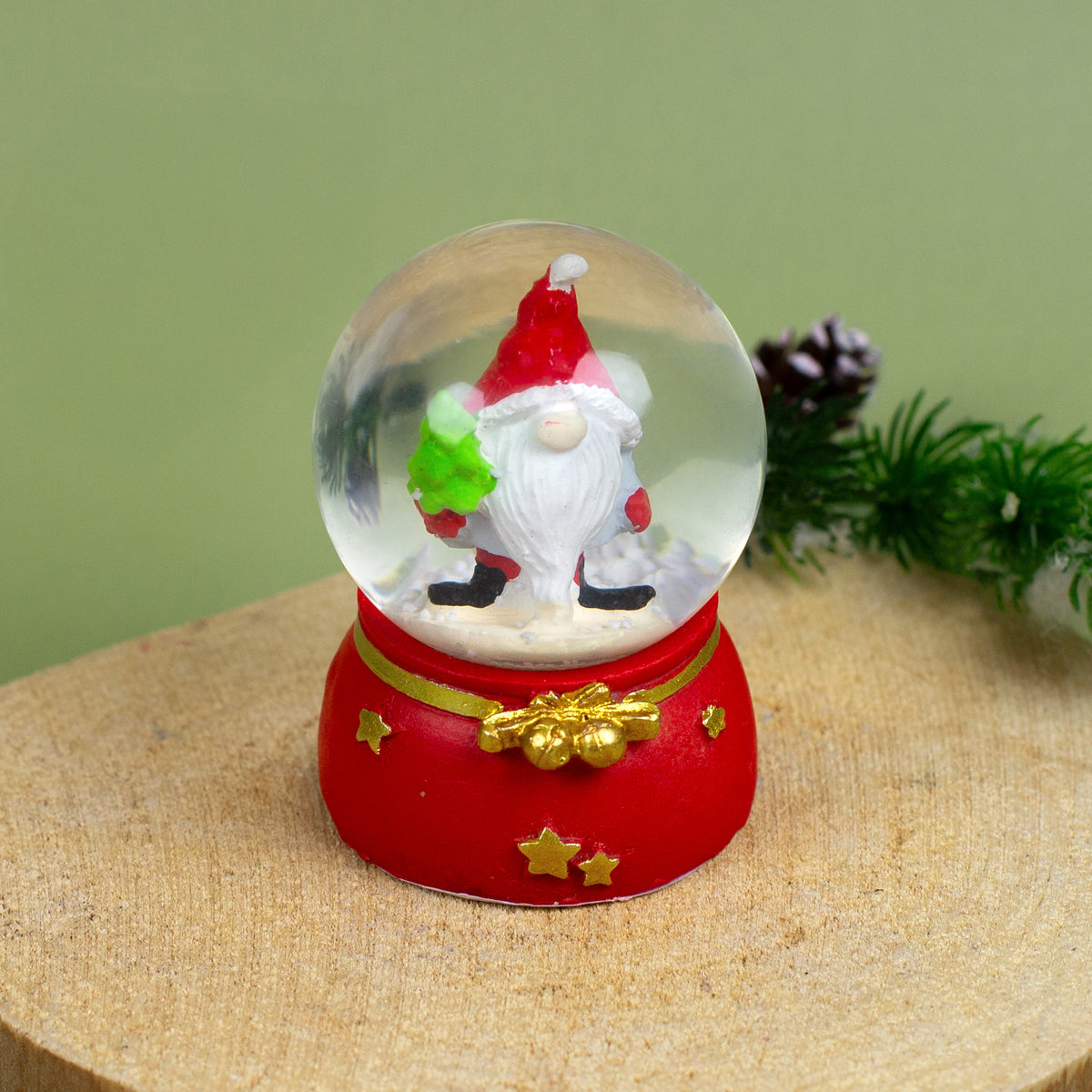 Mini-Schneekugel mit Wichtel und Sternmotiv, auf hellem Untergrund mit Weihnachtssternen