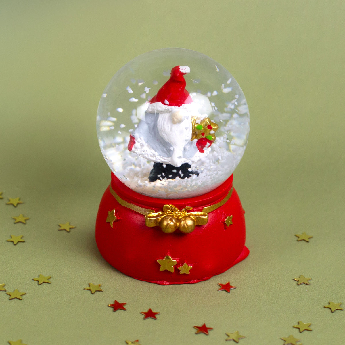 Detailaufnahme einer Schneekugel mit Wichtel, der einen goldenen Stern hält, klassisch weihnachtlich