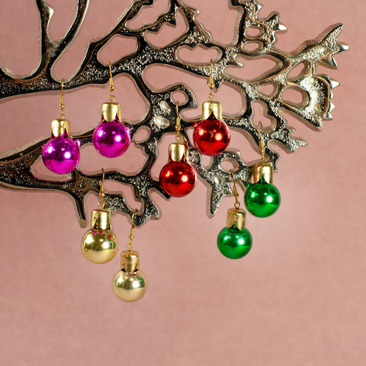 Vier Paar Weihnachtskugel-Ohrringe in Pink, Gold, Rot und Grün hängend an silbernem Dekobaum