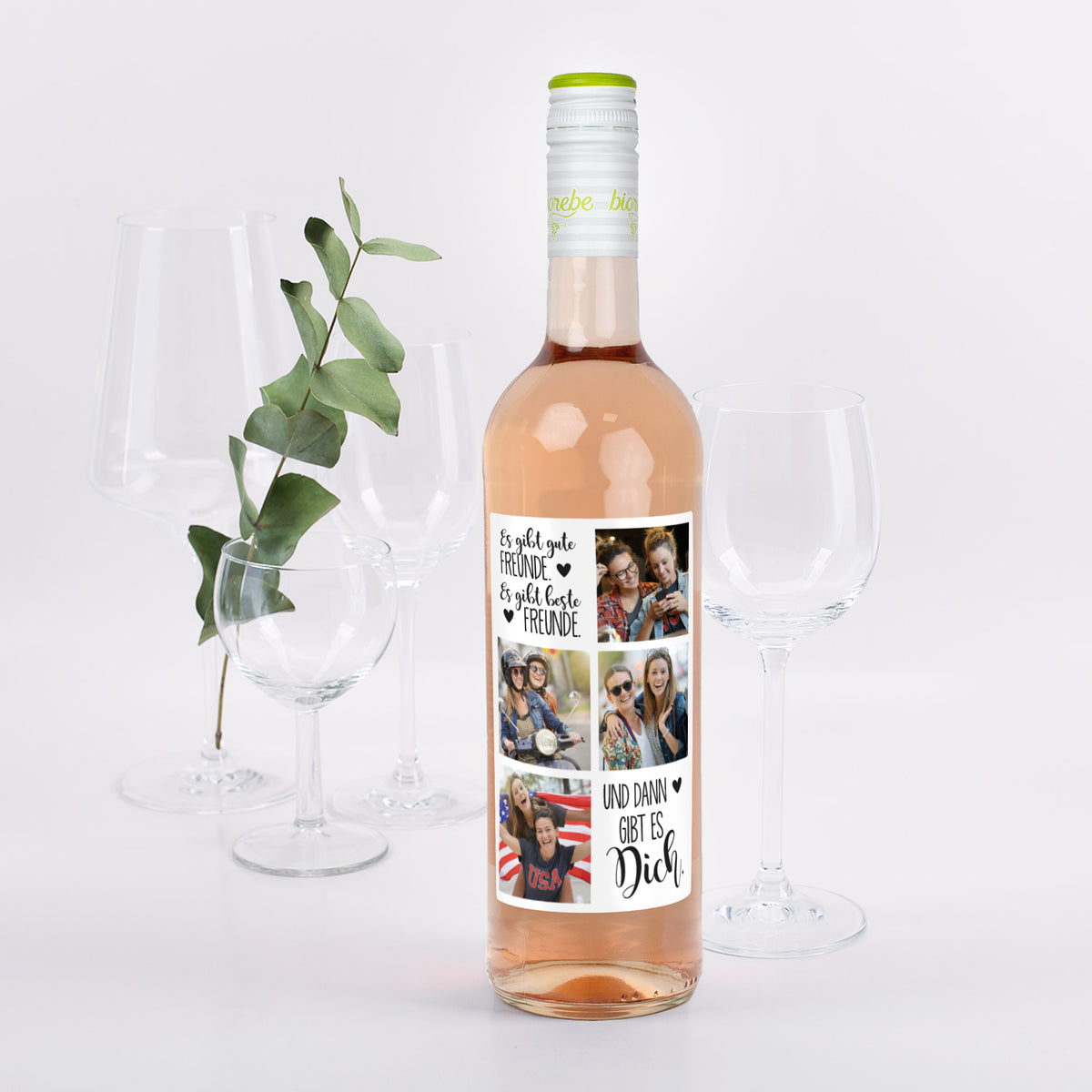 Flasche Roséwein mit personalisiertem Freunde-Motiv „Es gibt gute Freunde, es gibt beste Freunde, und dann gibt es Dich“ und vier Foto-Platzhaltern, dekoriert mit Weingläsern und Eukalyptuszweig.
