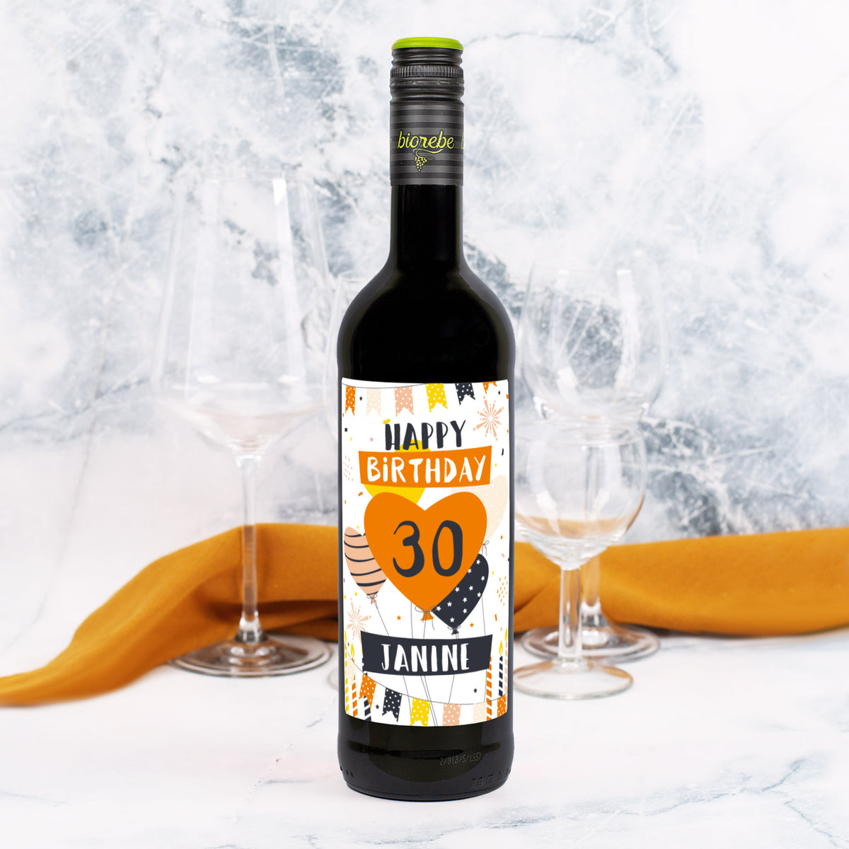 Weinflasche Rotwein mit Geburtstags-Etikett „Happy Birthday 30 Janine“ in Orange und Schwarz, dekoriert mit Luftballons und Girlanden, auf Tisch mit Gläsern.