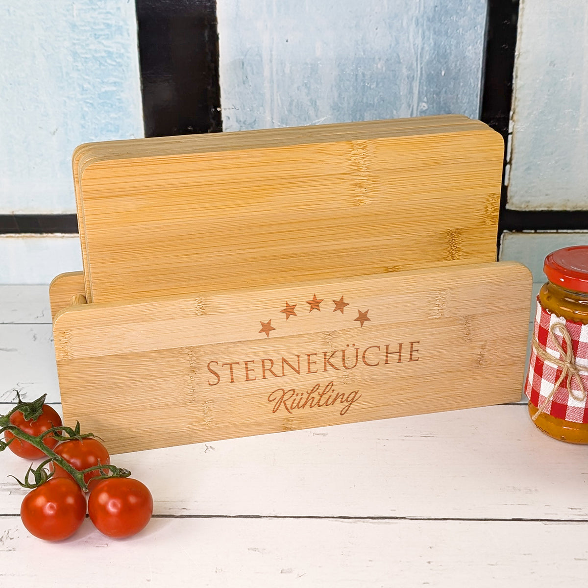Schneidebrett-Set aus Bambus mit Halter und Gravur „STERNEKÜCHE“ und Name „Rühling“, daneben Cocktailtomaten