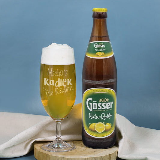 Bierglas „Radler für Radler“ mit Gravur und Flasche Gösser NaturRadler auf Holzbrett vor blauem Hintergrund