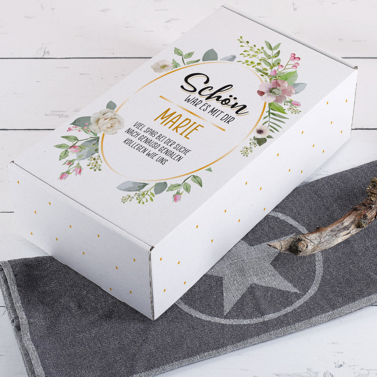 Geschenkbox mit Blumendekor und Aufschrift „Schön war es mit dir – Marie“ liegend