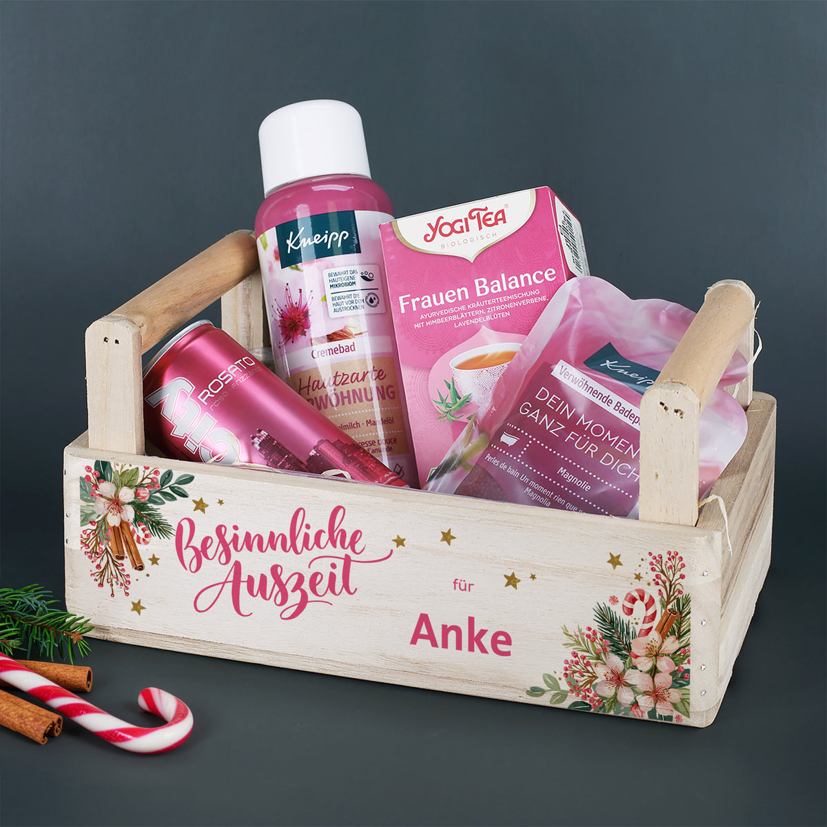 Personalisierter Weihnachtskorb „Besinnliche Auszeit für Anke“ mit Wellnessprodukten, Tee und City Rosato auf dunklem Hintergrund