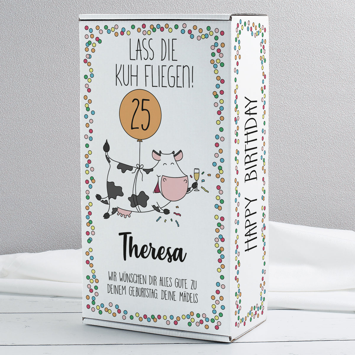Geschenkbox „Lass die Kuh fliegen!“ mit Konfetti-Rand, Kuh-Motiv und Ballon, personalisiert mit Name und Zahl