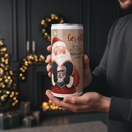 Bierdose mit Weihnachtsmann-Design, Foto im Lebkuchenherz und Name, gehalten in zwei Händen vor weihnachtlicher Kulisse.
