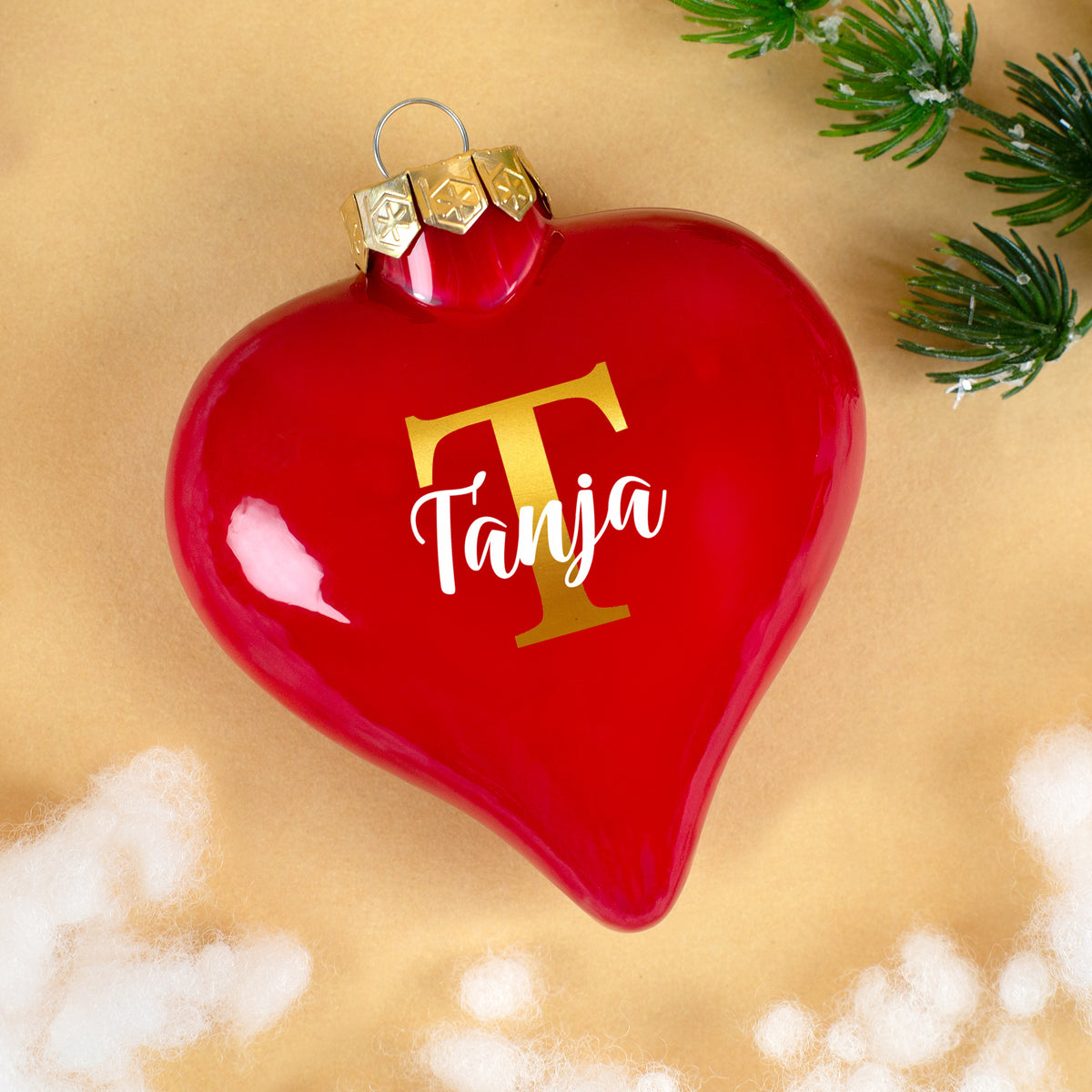 Rote Herz-Christbaumkugel mit goldener Initiale T und Name Tanja auf hellem Hintergrund
