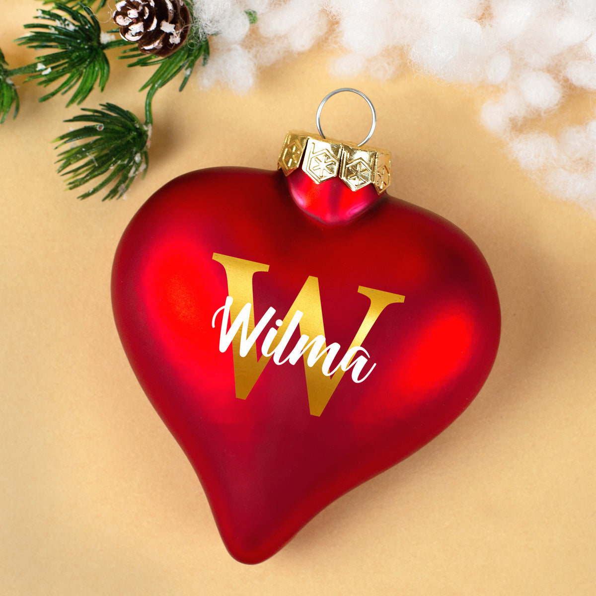 Herzförmige Christbaumkugel mit goldener Initiale W und Name Wilma auf weihnachtlichem Hintergrund