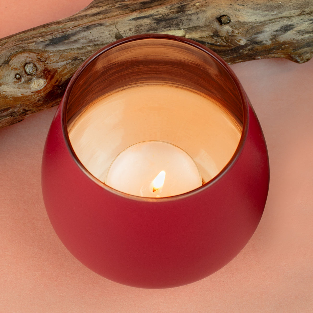 Rotes Windlicht mit warmem Kerzenlicht und kupferfarbenem Innenraum