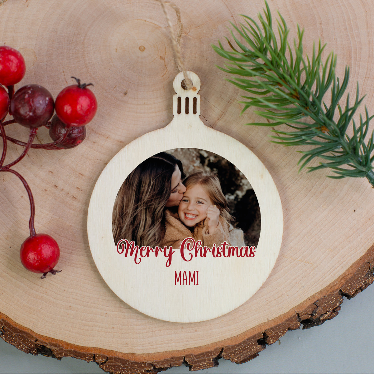 Weihnachtsbaumanhänger aus Holz mit Foto von Mutter und Tochter, Text „Merry Christmas Mami“, auf Holzscheibe mit Tannenzweig.