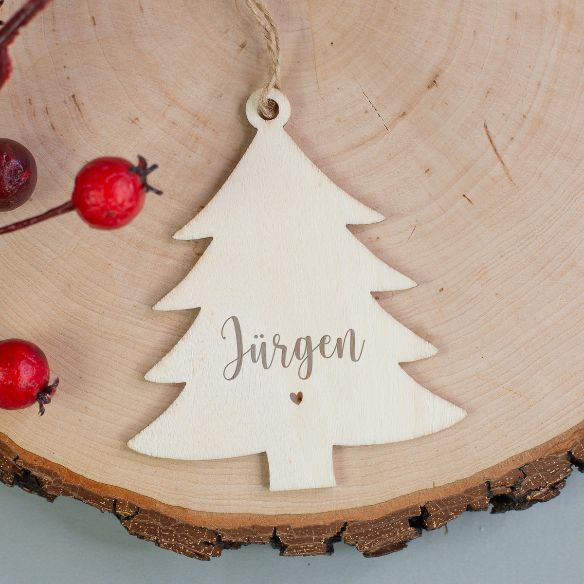 Holzanhänger in Tannenbaumform mit Gravur „Jürgen“ und kleinem Herzmotiv, dekoriert mit roten Beeren.