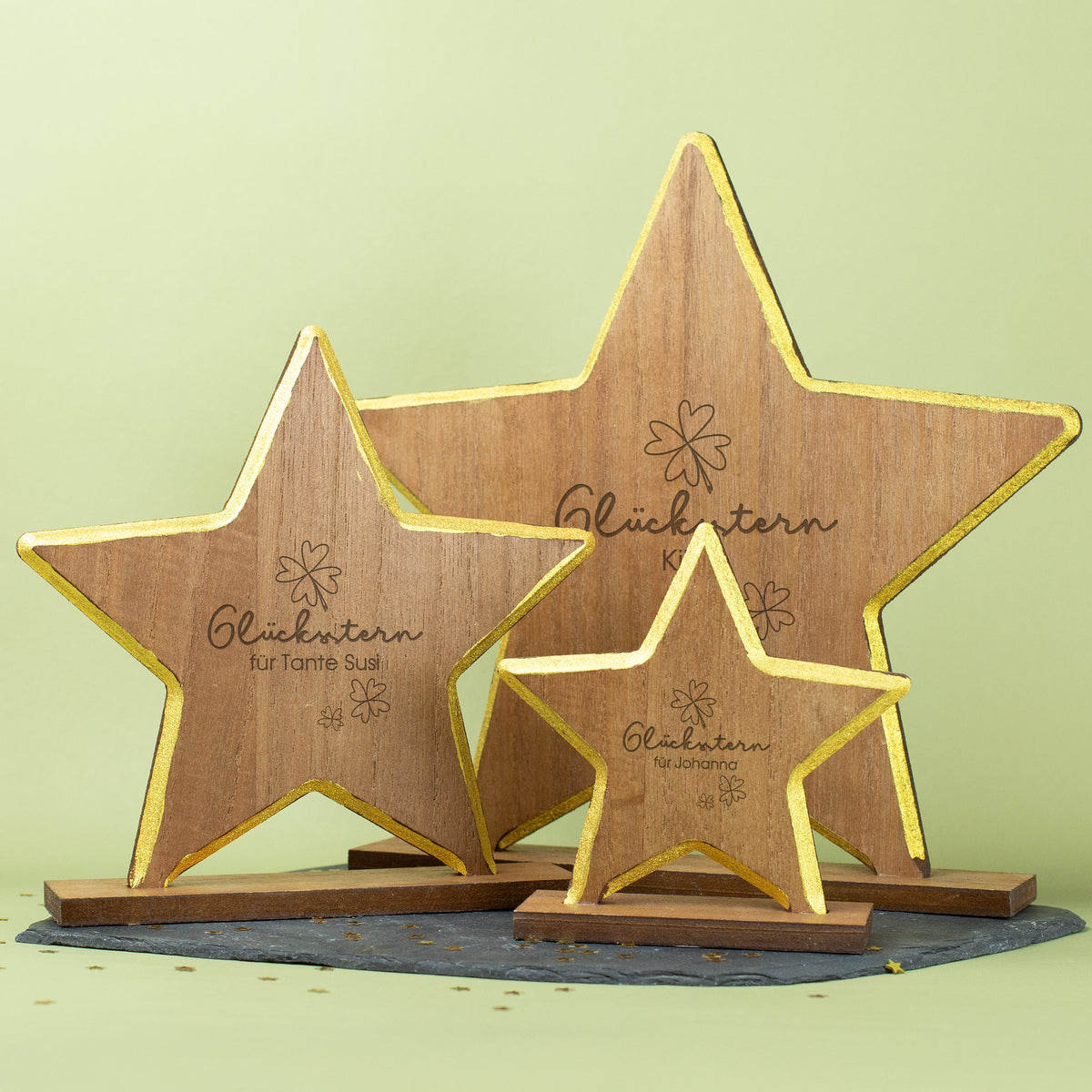 Graviertes Holzdeko-Sternmotiv mit Namensgravur und goldener Kante als Geschenk zu Weihnachten, alle drei Größen auf hellem Hintergrund.