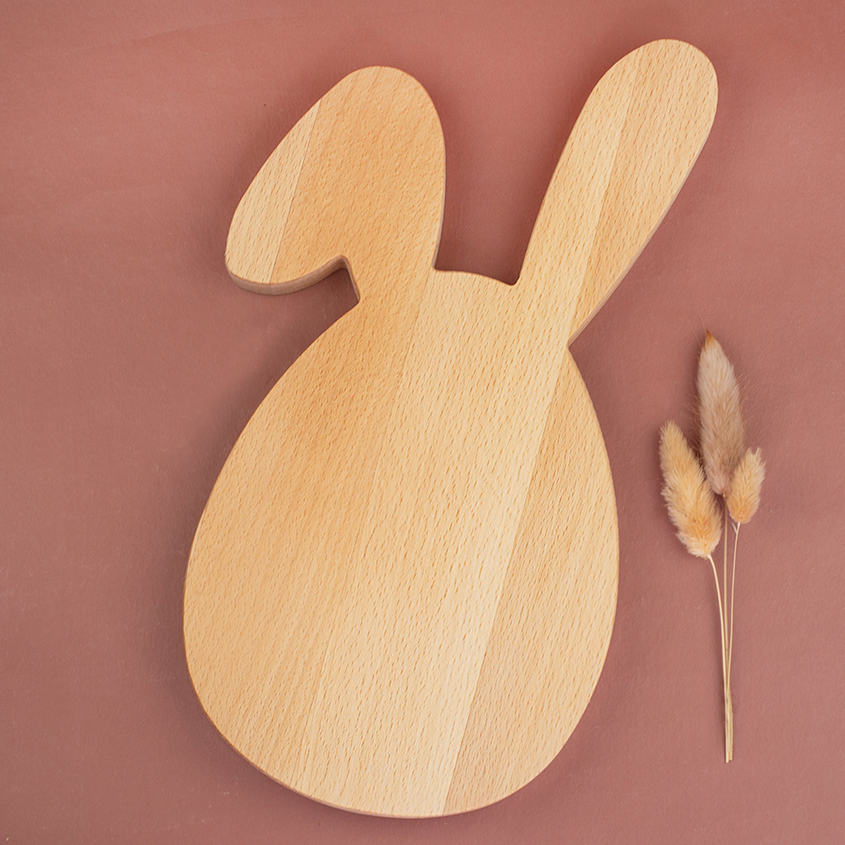 Rückseite des Holzbrettchen in Hasenform für Kinder auf rosa Hintergrund