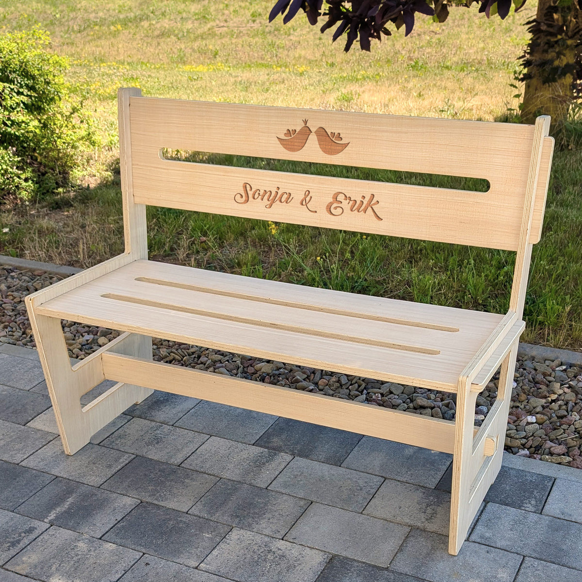 Personalisierte Holzbank mit Gravur "Sonja & Erik" und Vogelmotiv auf Terrasse im Grünen