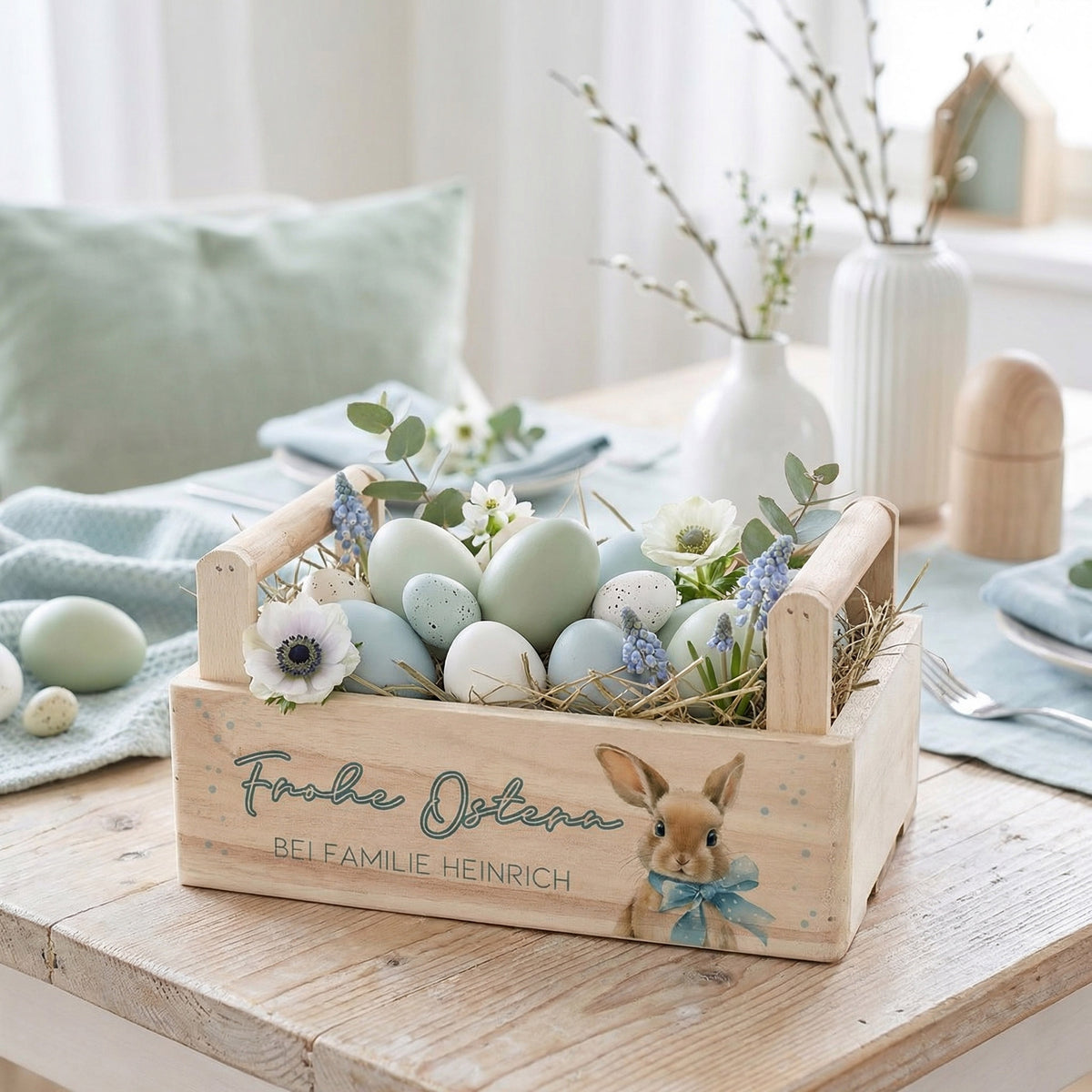 Pflanzkorb aus Holz mit Mittelgriff, Hasenmotiv und Wunschtext als Osterkiste mit dekorativem Nest aus Eiern und Frühlingsblumen