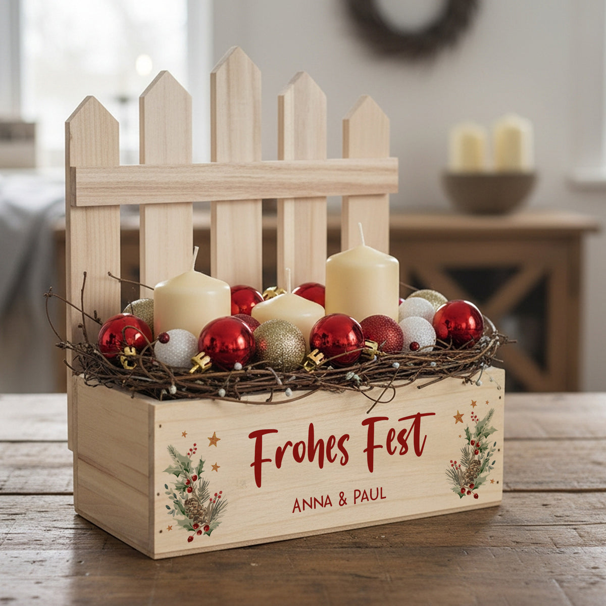 Weihnachtlich dekorierte Geschenkkiste mit Zaunelement, Kerzen und roten Christbaumkugeln auf einem Holztisch