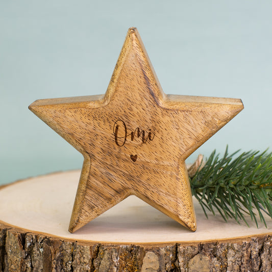 Holzstern mit Gravur „Omi“ als Weihnachtsdekoration auf einem Holztablett mit Tannenzweig