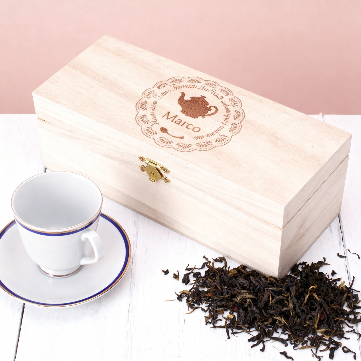Tee-Geschenkbox mit Gravur einer Teekanne und Name Marco, dekoriert mit losen Teeblättern und Teetasse.