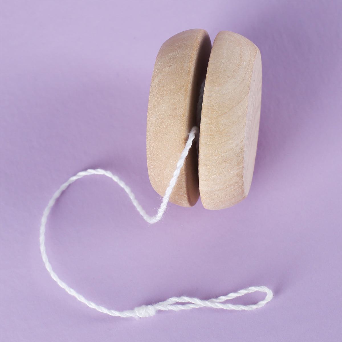 Seitenansicht des naturfarbenen Holz-Yo-Yos auf lila Untergrund