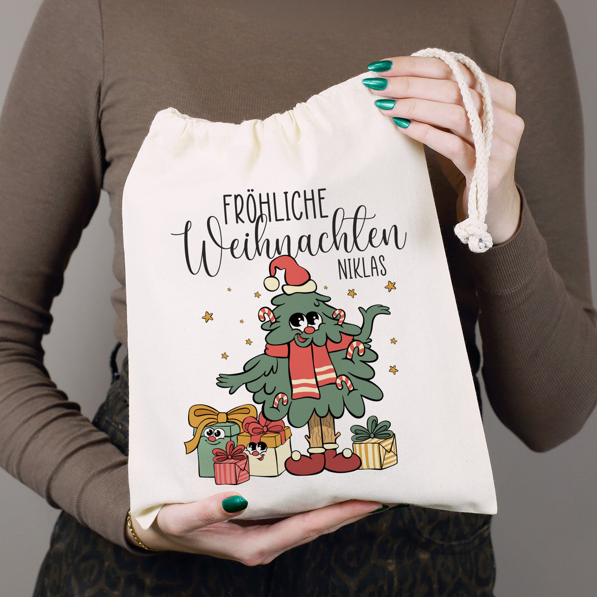 Personalisierter Stoff Geschenksack mit Name Niklas und Weihnachtsbaum Motiv in der Hand