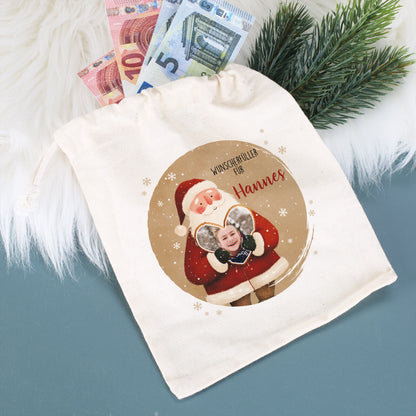 Kleiner Baumwollbeutel mit Weihnachtsmann-Motiv und Foto im Herz, Text „Wunscherfüller für Hannes“, mit Geldscheinen und Tannenzweig dekoriert – ideal für Geldgeschenke.