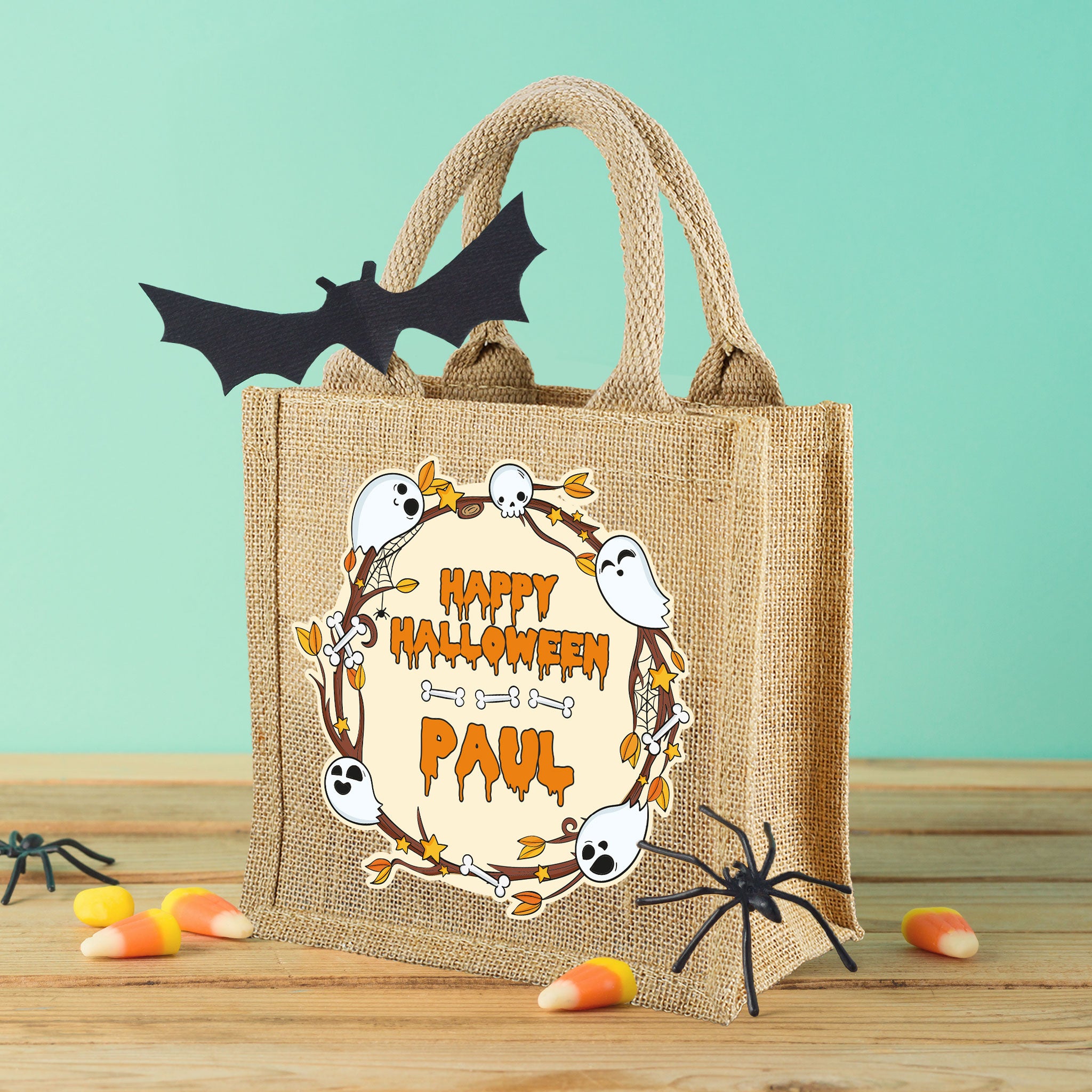 Personalisierte Halloween-Jutetasche mit „Happy Halloween“-Motiv und Name, auf Tisch mit Deko