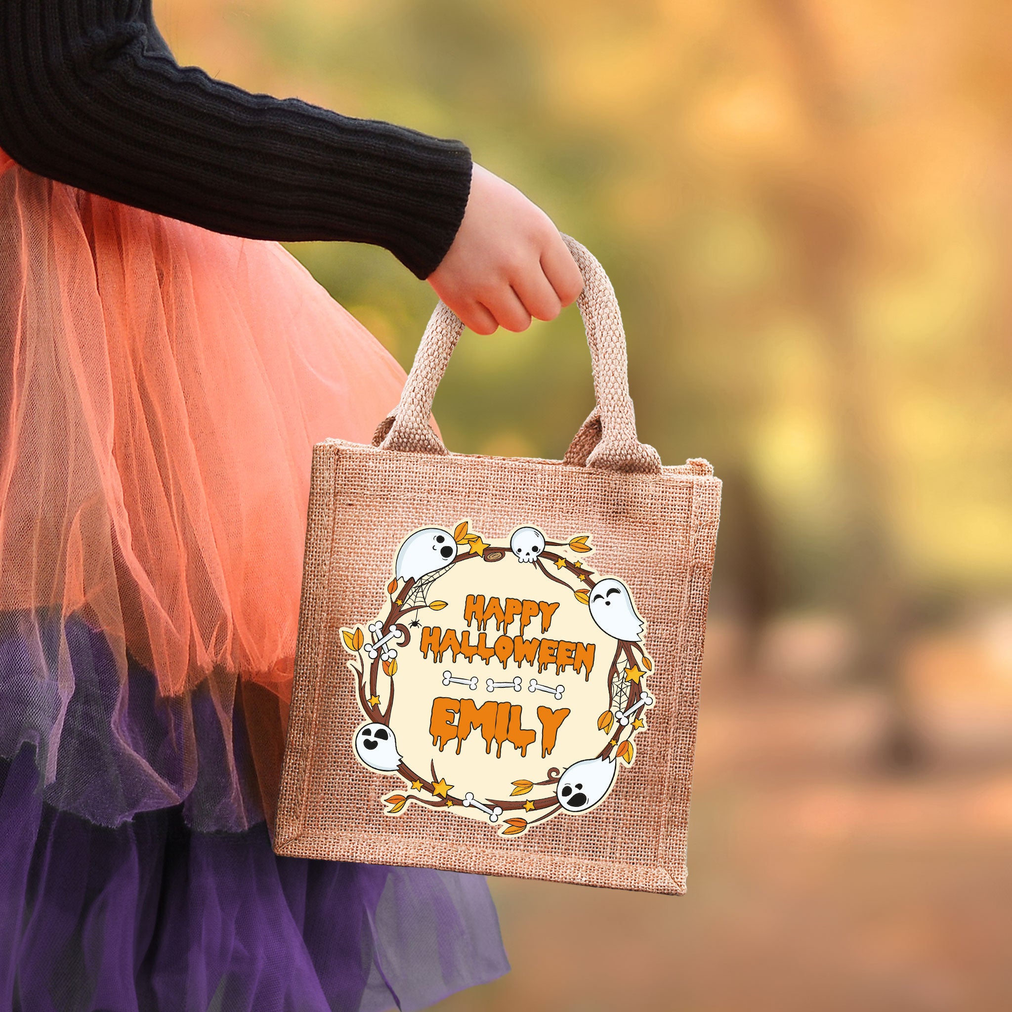 Halloween-Jutebeutel mit Name, getragen von Kind im Kostüm, Kürbis-Design im Hintergrund